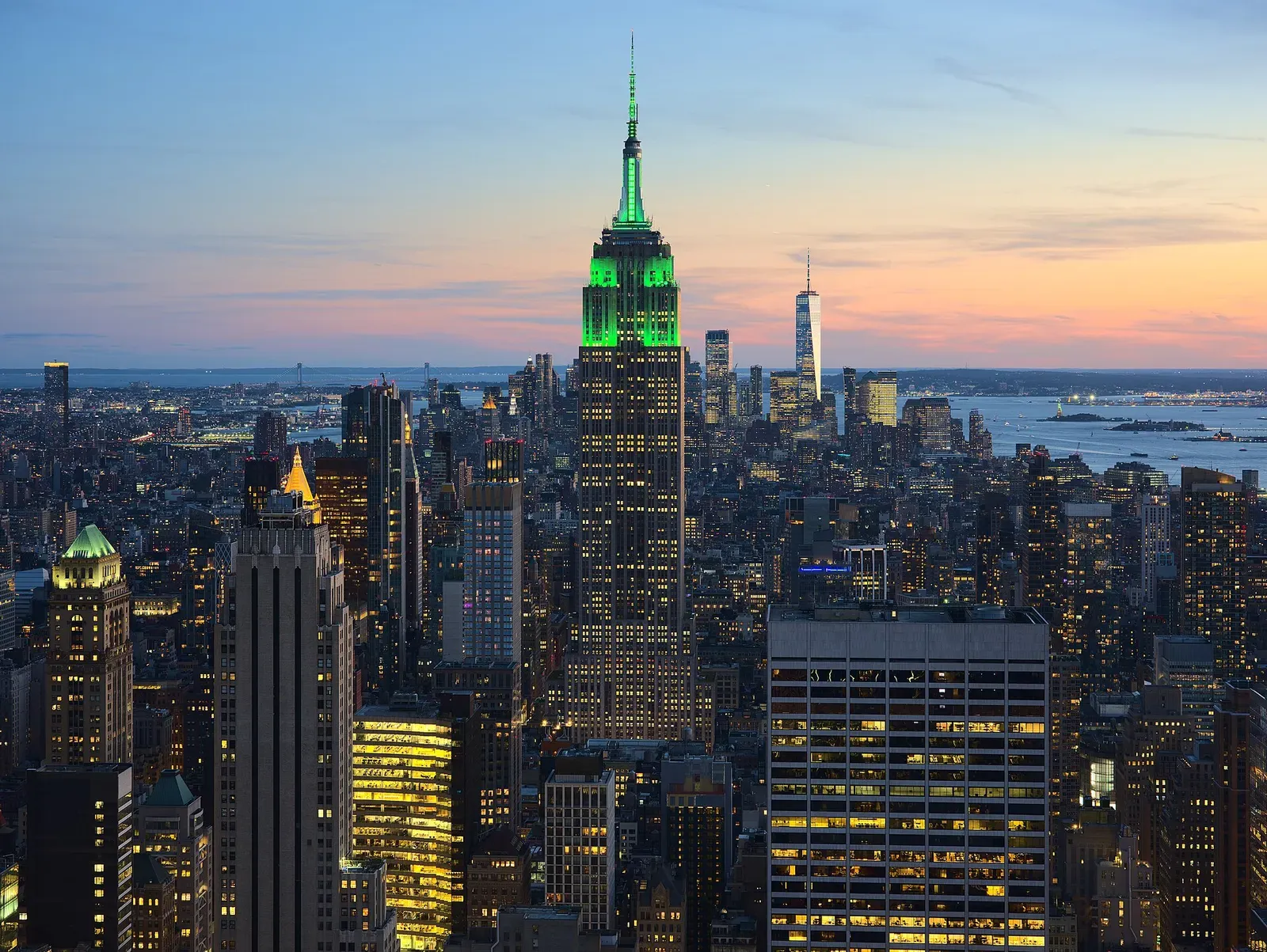 View of the Empire State Building in New York City from the Top of the Rock at 30 Rockefeller Plaza during sunset. The tower was illuminated in green…